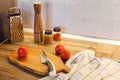 wooden board with knife, tomatoes, olive oil, spices in glass jar, pepper mill on modern kitchen countertop. cooking food. Royalty Free Stock Photo