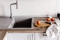 wooden board with knife, tomatoes, towel, spices on modern kitchen countertop near granite sink and steel faucet. cooking food. Royalty Free Stock Photo