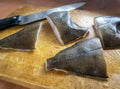 On a wooden board are large pieces of flounder and a knife. Raw fish is sliced and processed for eating. Cooking fish dishes Royalty Free Stock Photo