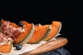 Wooden board with melon,  and blueberries on table against black background Royalty Free Stock Photo