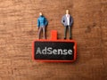 Wooden board and miniature people with text AdSense