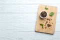 Wooden board with mixed pepper corns and basil leaves on white table. Space for text Royalty Free Stock Photo