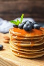 Wooden board with pancakes, syrup and blueberries on table, clo