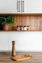 wooden board with pepper mill and knife on modern kitchen countertop and shelves with food ingredients and spices in glass jars. Royalty Free Stock Photo