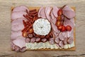 Wooden board with pieces of meat, feta cheese and vegetables, on the kitchen counter, top view. Royalty Free Stock Photo