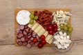 Wooden board with pieces of meat, feta cheese and vegetables, on the kitchen counter, top view. Royalty Free Stock Photo