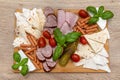 Wooden board with pieces of meat, feta cheese and vegetables, on the kitchen table, top view.