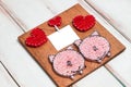 Wooden Board with pink pigs and red hearts and text frame on white wooden diagonal background. Copy space.