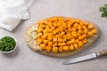 Wooden board with pumpkin cubes and minced garlic with parsley on a beige textured background. Cooking delicious vegan Royalty Free Stock Photo