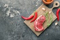 Wooden board with raw meat and spices on grey textured background Royalty Free Stock Photo