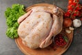 Wooden board with raw spiced turkey and ingredients on grey background