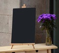 Wooden board for restaurant menu with empty space to add text standing at restaurant entrance with flower pot Royalty Free Stock Photo