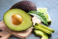 Wooden board with ripe avocados on grey textured background