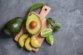 Wooden board with ripe avocados and lime on grey textured background Royalty Free Stock Photo