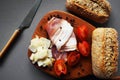 Wooden board with slices of bacon, parmesan, cherry tomatoes, black peppercorns next to bread and knife Royalty Free Stock Photo