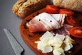 Wooden board with slices of bacon, parmesan, cherry tomatoes, black peppercorns next to bread and knife Royalty Free Stock Photo