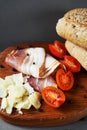 Wooden board with slices of bacon, parmesan, cherry tomatoes, black peppercorns next to bread and knife Royalty Free Stock Photo