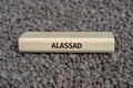 Wooden board on small pebbles on which the word ALASSAD is shown Royalty Free Stock Photo