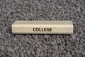 Wooden board on small pebbles on which the word COLLEGE is shown