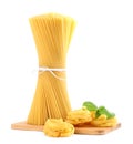 Wooden board with spaghetti, tagliatelle pasta and basil leaves isolated on white