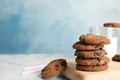 Wooden board with stack of tasty chocolate chip cookies on table. Royalty Free Stock Photo