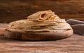 Wooden board with stack of tasty thin pancakes on table