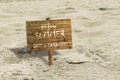 Wooden board stuck in the sand with text ENJOY SUMMER LOST IN PARADISE