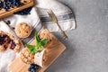 Wooden board with tasty blueberry muffins on grey table Royalty Free Stock Photo