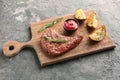 Wooden board with tasty grilled steak, potato and sauce on table Royalty Free Stock Photo