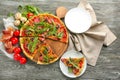 Wooden board with tasty pizza and plate with slice on table Royalty Free Stock Photo