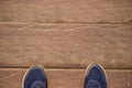 Wooden board top view photo with man feet. Worn male shoes on dusty wooden floor. Rough timber bridge Royalty Free Stock Photo