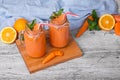 A wooden board with two mason jars with carrot smoothie, basil, oranges anf leaves of mint on a light background. Royalty Free Stock Photo