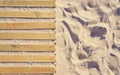 Wooden boards as a path next to beach sand. Summer background with copy space as a top view Royalty Free Stock Photo