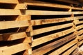 Wooden boards close up. Lots of boards stacked on top of each other in a warehouse. Perspective angle of wooden boards