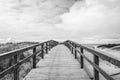 Wooden boardwalk extending towards a cloudy beach view Royalty Free Stock Photo