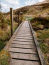 Wooden boardwalk over muddy swampy boggy ground in the UK country side at Rivington Pike .