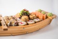 Wooden boat with lots of sushi with ginger and wasabi