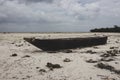 Wooden boat on low tide. Zanzibar beach with old nautical vessel. African seascape with cloudy sky. Empty coast of Indian Ocean. Royalty Free Stock Photo