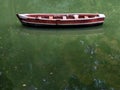 Wooden boat without people with green lake water reflection, row boat side view. Royalty Free Stock Photo