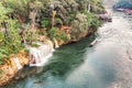 Wooden boat sailing river kwai with waterfall in tropical rainforest