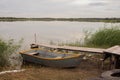 A wooden boat stands on the shore of the lake next to a wooden pier Royalty Free Stock Photo