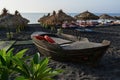 Wooden boat, tanning beds and straw umbrellas on Perissa beach, Santorini island, Greece Royalty Free Stock Photo