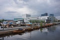 Wooden boats docked on the Inner Oslofjord with the Oslo Opera House standing in the background during an cloudy afternoon