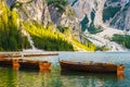 Wooden boats on the popular tourist lake Braies with amazing view of Dolomites Alps.