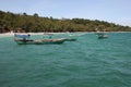 Wooden boats in pristine turquoise water near tropical island.