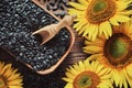 Wooden bowl of black sunflower seeds, beautiful yellow sunflowers on wooden board Royalty Free Stock Photo