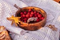 Wooden bowl with bright red ripe hawthorn berries on beige plaid with yellow fallen autumn oak leaves Royalty Free Stock Photo