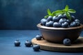 A wooden bowl brimming with fresh, juicy blueberries, sitting prominently on a table, Fresh blueberries in a wooden bowl on a blue Royalty Free Stock Photo