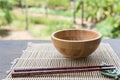 Wooden bowl with chopsticks on bamboo mat on wooden table in the garden Royalty Free Stock Photo