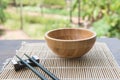 Wooden bowl with chopsticks on bamboo mat on wooden table in the garden Royalty Free Stock Photo